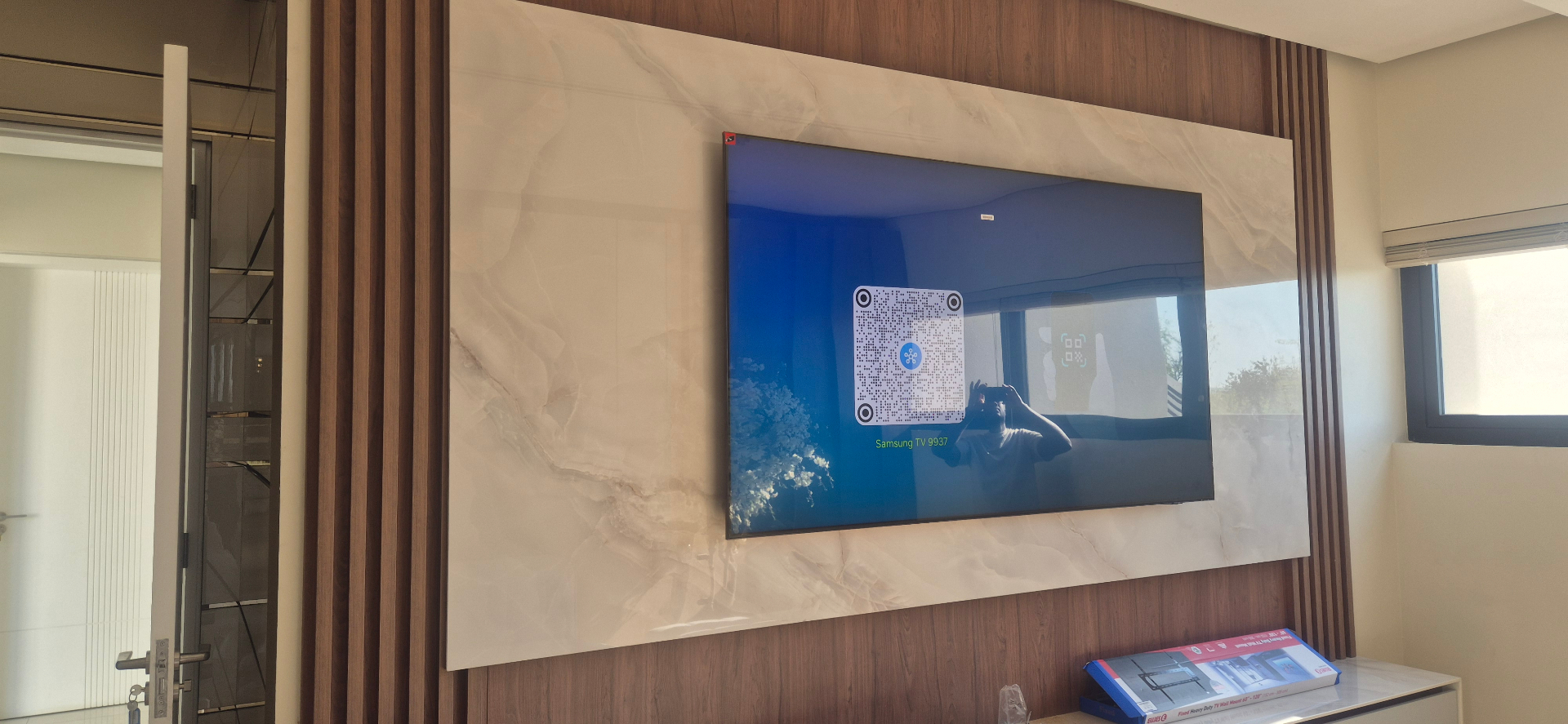 Samsung TV mounted on a marble panel with walnut slat surround