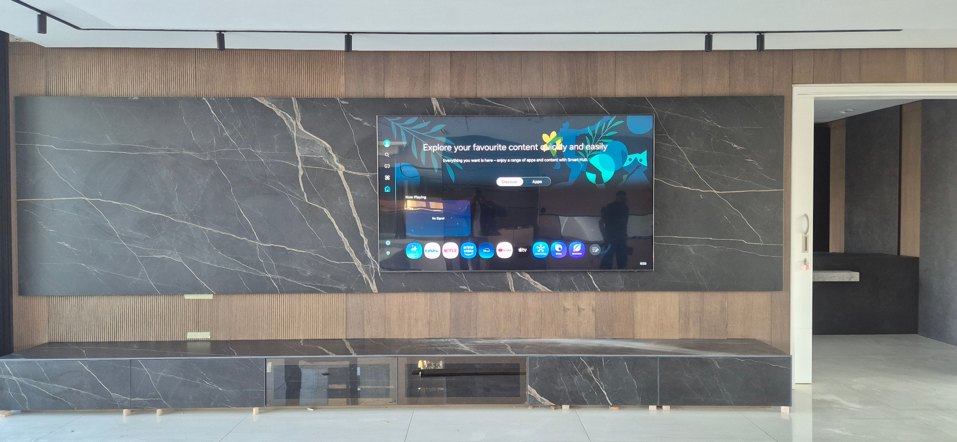 Large TV mounted on a marble feature wall with soundbar and slatted wood panelling