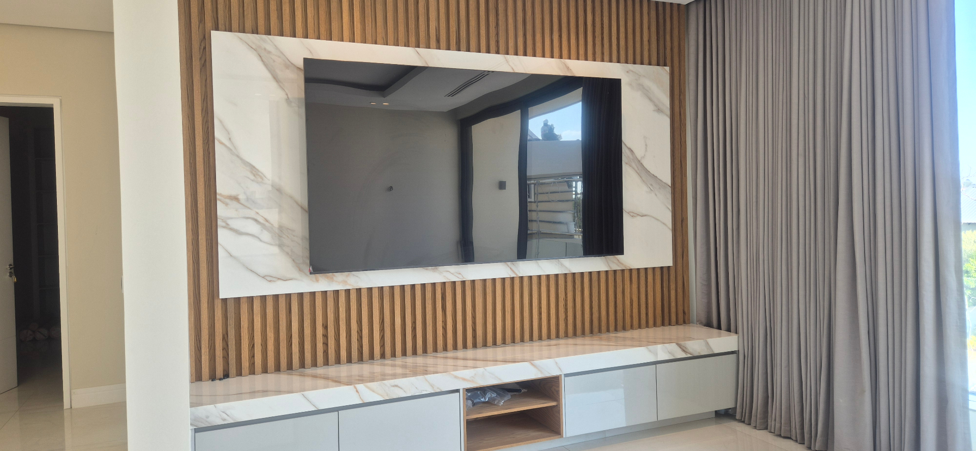 Wide TV wall mounting with hidden cables above a marble media console
